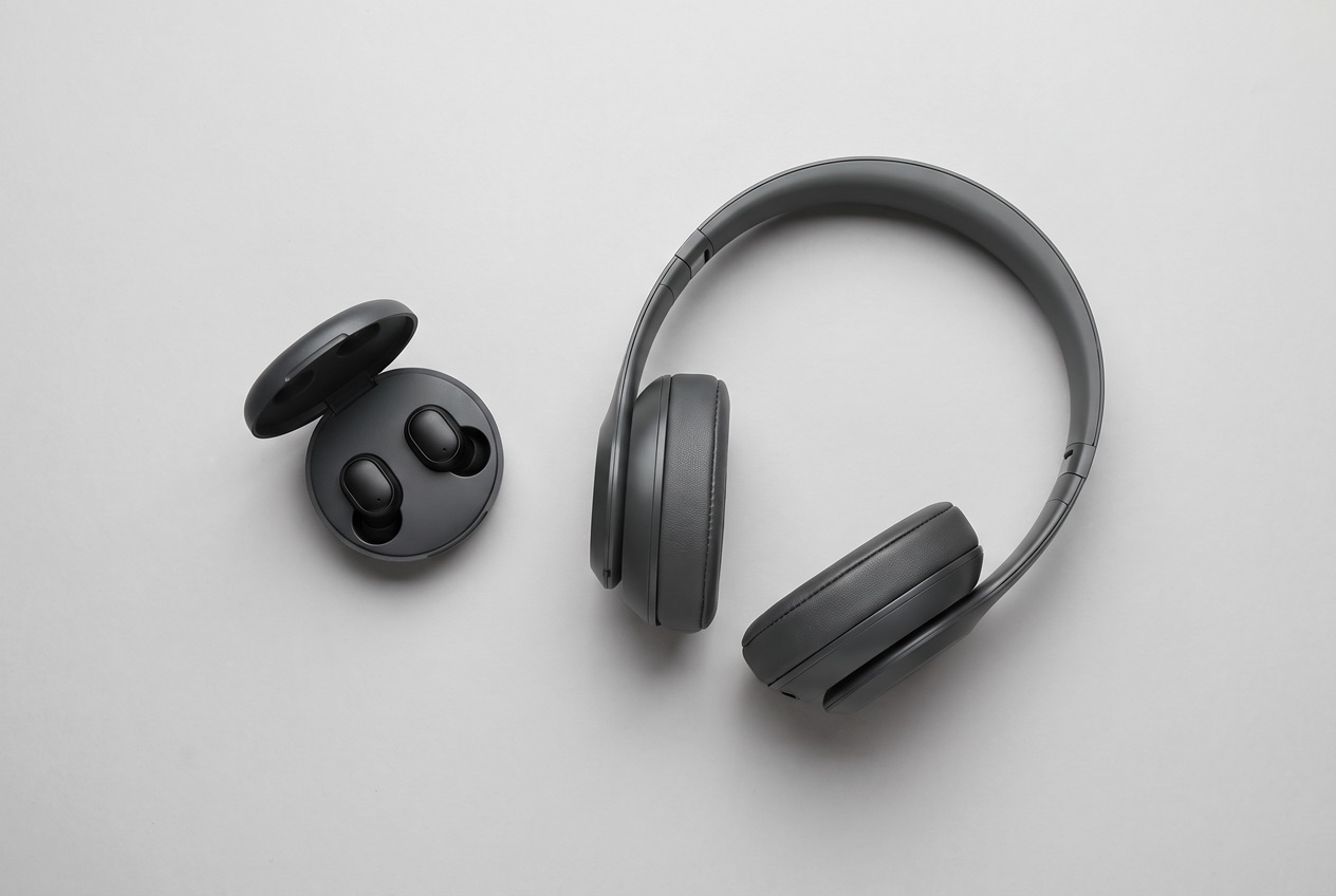 Verschiedene Kopfhörer-Bauformen im Vergleich – Over-Ear-Kopfhörer neben In-Ear-Kopfhörern mit Ladeetui