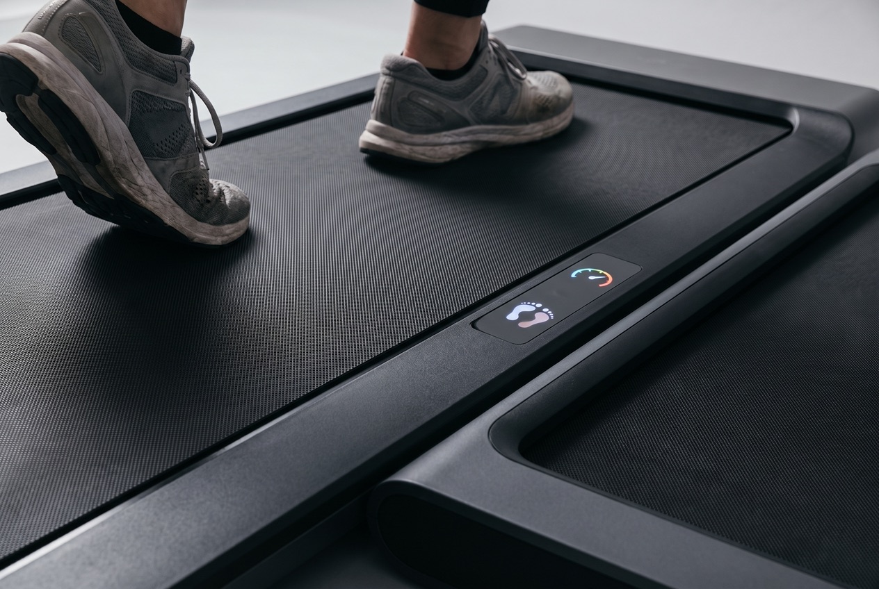 Nahaufnahme der Lauffläche und des Displays eines Walking Pads mit Anzeige von Tempo und Schritten